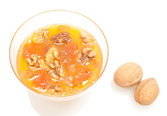 dried apricots and walnuts in a glass bowl with honey isolated on white