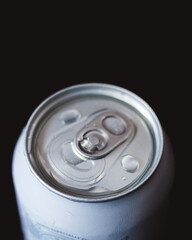 Aluminum can of beverage covered with water drops on black background, closeup