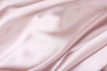 Pink satin fabric. Textile background. Powdery color. Waves and folds of fabric.