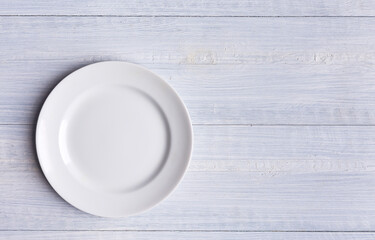 White soft wood surface as background. White wood pattern with a white plate or dish. Close-up image.