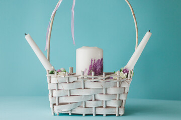 white wedding candles on bacsket on blue background isolated. Wedding decor.