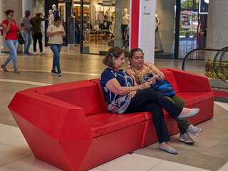 Women seated in mall chair. Resting after shopping