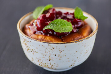 Tender soft dessert in a bun with berries, jam and mint.