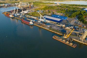 Marine cranes at the pier ready for loading bulk cargo onto a barge. Aerial view.