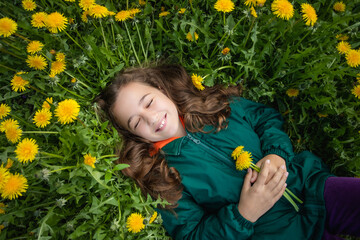 Close-Up Of Little Girl Lies On Grass With Dandelions.
