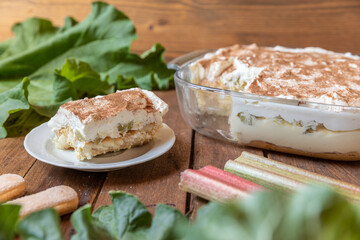 selbstgemachtes Tiramisu mit Rhabarber, Creme, Sahne, Zimt, Löffelbiscuit und Mascarpone auf einem Tisch aus Holz