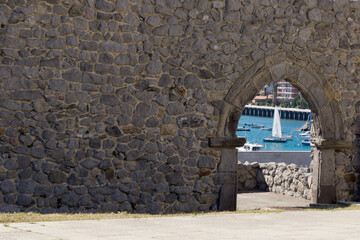Boats in the port of Castro Urdiales, between the arch of the stone wall in the region of Cantabria in northern Spain.