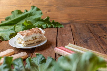 selbstgemachtes Tiramisu mit Rhabarber, Creme, Sahne, Zimt, Löffelbiscuit und Mascarpone auf einem Tisch aus Holz