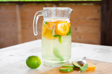 Fototapeta premium lime, mint and orange lemonade,on an old wooden table, a refreshing drink in the hot summer. Cooling, pleasant taste. Ingredients, homemade recipe