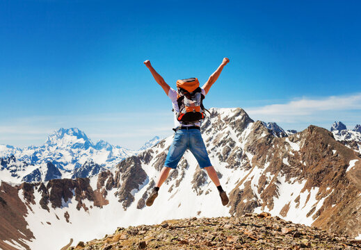 Beautiful mountain landscape with and bouncing man. Extreme sports. A man jumping on top of a mountain with a backpack.