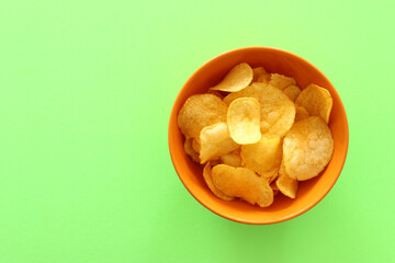 Top view image of potato chips slices in the bowl over pastel green background