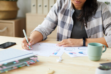 Cropped portrait of young mixed-race woman drawing graphs and charts while planning project at home, copy space