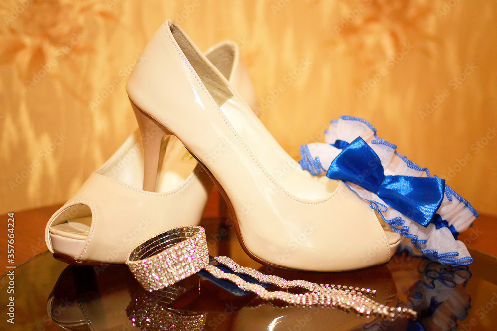 Wall mural bridal shoes next to garter and jewelry close-up