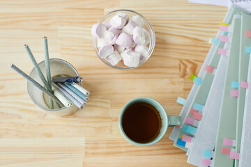 Top down view of work or studying supplies with tea mug on wooden table background, copy space