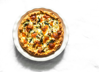 Canned tuna, mozzarella, spinach, potatoes rustic pie on a light background, top view