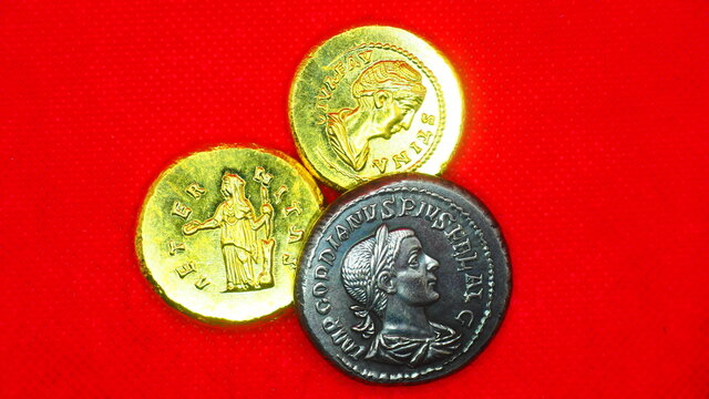 Silver and gold roman coins on red background