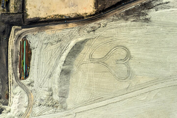Top view on a heart drawn in quarry from coal. Heart from sand.
