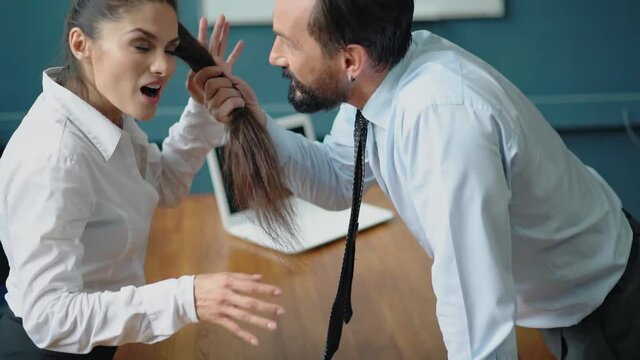 Work violence. Man grabs woman hair telling bad stuff standing at the table. The girl in raised tones responds to the screams of the boss standing against her. Gender Conflict Concept. Prores 422.