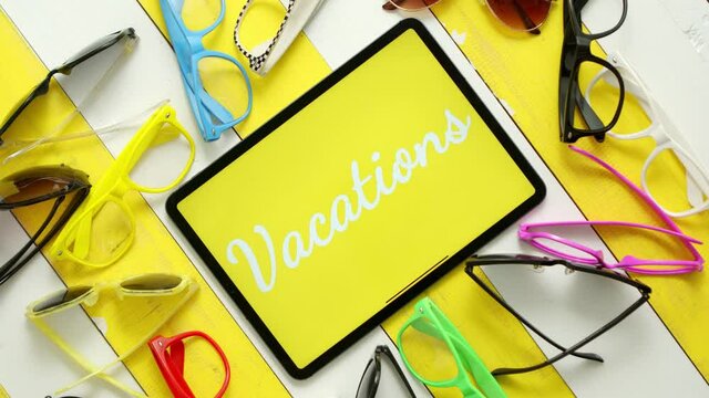 Various style, shape and colour sunglasses. Tablet in the middle with text VACATIONS.
