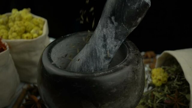 Cumin seeds falling into the granite mortar with pestle in slow motion. Healthy and organic food, herb medicine, natural care, aromatherapy and organic cosmetics concept.