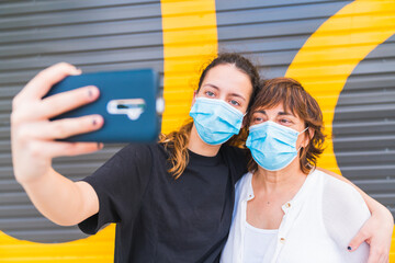 Mother and daughter making a selfie in the street protected by a mask. Family protected with a...