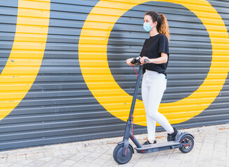New normal. young girl with a mask using an electric scooter. Woman using electric and ecological...