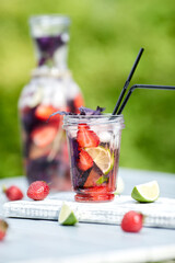 Delicious refreshing lemonade with basil, lime and strawberries. Summer drink with ice. Home made production.