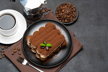 Classic tiramisu dessert on ceramic plate, milk or cream and cup of coffee on concrete background