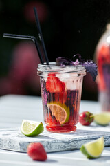 Delicious refreshing lemonade with basil, lime and strawberries. Summer drink with ice. Home made production.