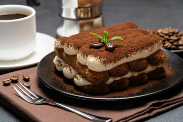 Classic tiramisu dessert on ceramic plate, milk or cream and cup of coffee on concrete background