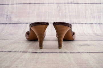 Fototapeta na wymiar Women's sandals on a wooden background. Fashionable summer sandals. Back view. Heels close-up.