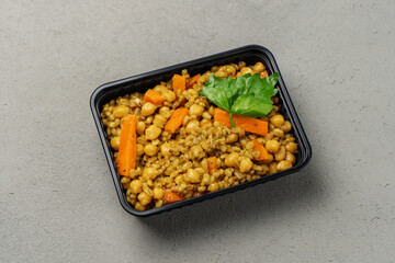 Vegetarian pilaf in a biodegradable shipping container decorated with greenery top view