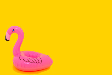 Pink inflatable flamingo isolated on yellow background
