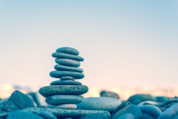 Stone cairn on natural background - blurred sea and sky. Concept balance, vacation relax.