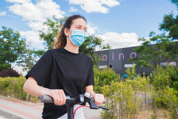 New normal. young girl with a mask using an electric scooter. Woman using electric and ecological...