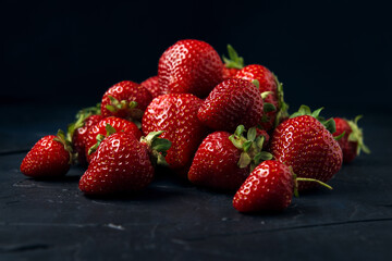 Ripe red strawberries on a dark blue background. Sweet fresh berries on a table.