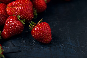 Ripe red strawberries on a dark blue background. Sweet fresh berries on a table. Space for text.