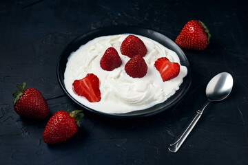 Plate with ice cream and strawberries on a dark blue background. Sweet dessert from fresh berries on table.