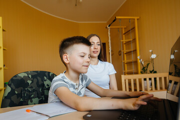 A mother and her child are engaged in distance learning at home in front of the computer. Stay at home, training