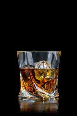 Glass of whiskey with cube ice on black background