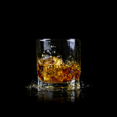 Splashing of whiskey out of glass isolated on black