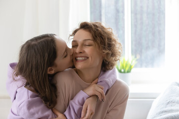 Cute teenage girl hug kiss in cheek happy young Caucasian mother show gratitude and love, caring teen daughter embrace cuddle smiling mom, congratulate greet with anniversary, family bonding concept