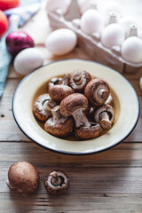 Raw eggs, fresh brown crimini mushrooms and onion on wooden background. Ingredients for cooking