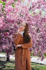 A beautiful young girl walks on a spring day in a blooming Apple orchard. Lifestyle, recreation