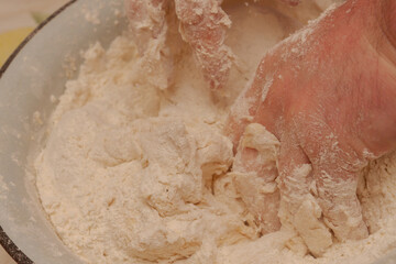 Fototapeta premium Cooking dough in a white metal bowl at home