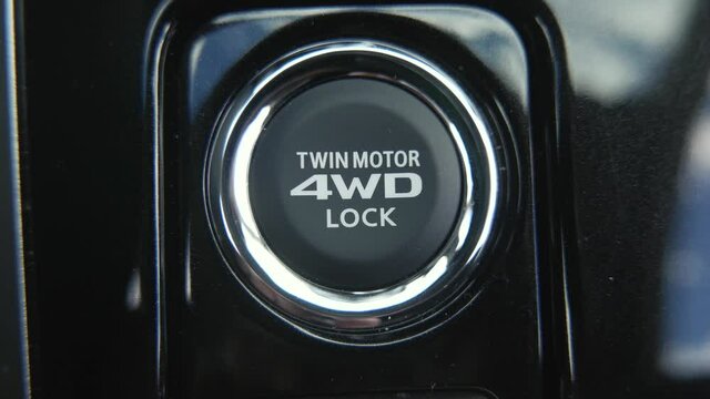 Pressing the all-wheel drive lock button inside an SUV to lock the differential and get more traction during an off-road situations.