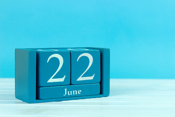 wooden calendar with the date of June 22 on a blue wooden background
