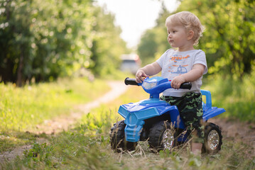 Baby boy is riding a toy car quad bike.