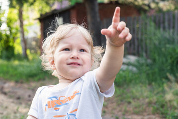A child boy is showing up by his index finger.
