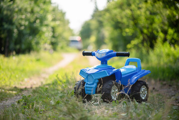 A toy quad bike on a green grass background.